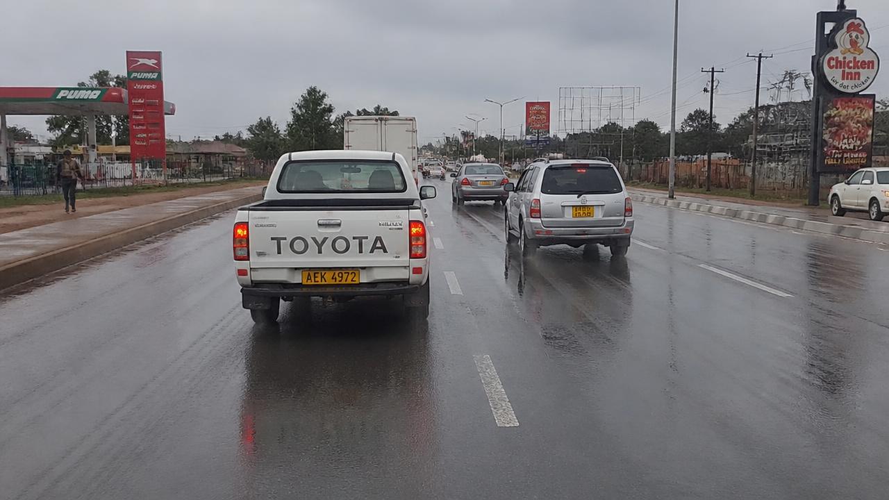 View through a windscreen of vehicles keeping a safe following distance on a wet Zimbabwean dual carriageway.