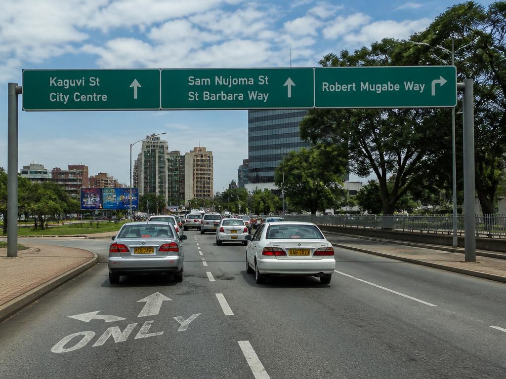 Multi-lane Zimbabwean city road with green overhead direction signboards, lane arrows and light traffic.